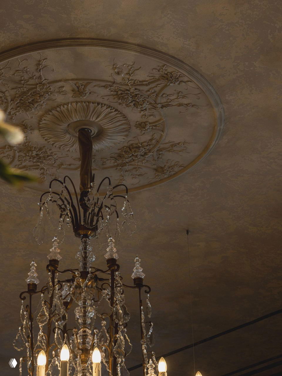 Столик рядом со стеклянной дверью и мраморной стеной: контраст тёплого паркета и мелкой мозаичной плитки в проходе ресторана.