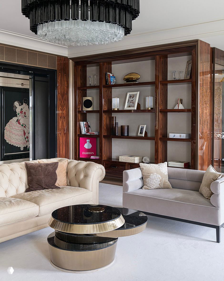 Классическая гостиная со светлыми диванами и тёмными деревянными мебельными нишами; коричневые акценты создают тёплую, элегантную атмосферу помещения.