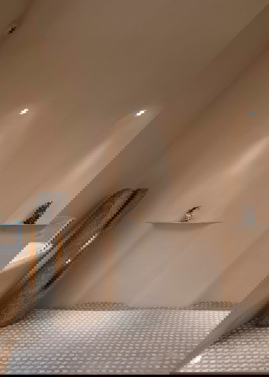 Ниши с подсветкой и керамическими полками для экспозиций, текстурный орнамент плиточного пола и скульптурные элементы в спокойной бежевой гамме.