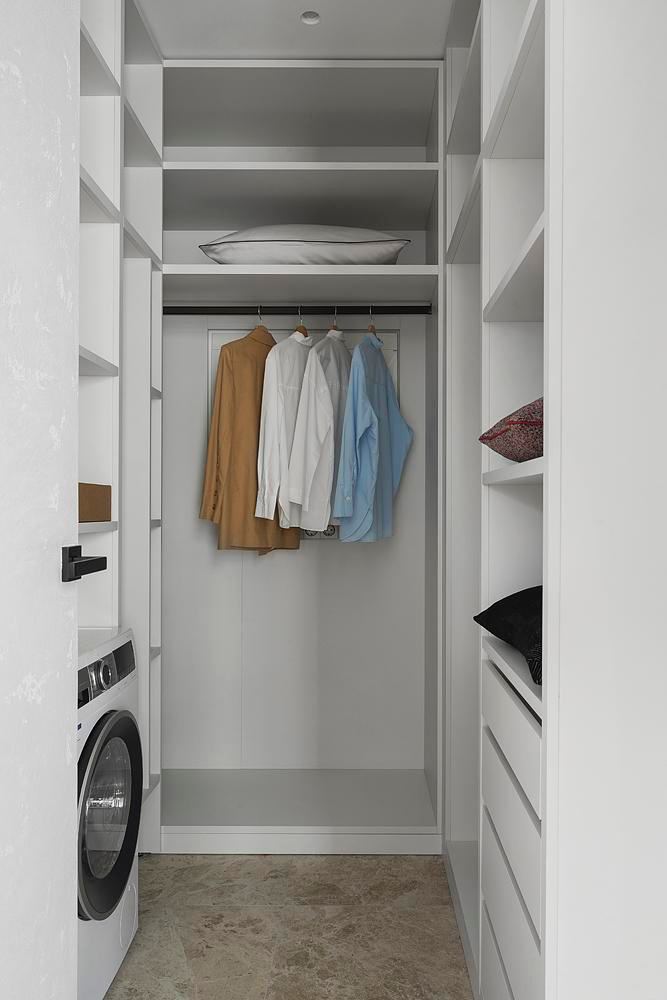 Гардеробная и прачечная в нише с открытыми полками, стиральной машиной и аккуратно висящей одеждой — функциональное использование площади в 45 м².