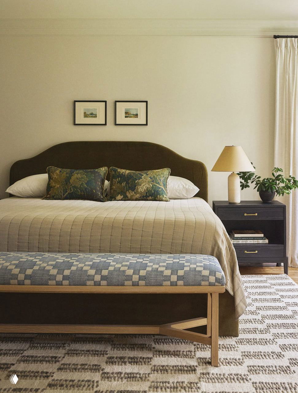 Спальня с большой кроватью в тёмной обивке, декоративными подушками и деревянной скамьёй у изножья на нейтральном ковре — уютный классический интерьер спальни.