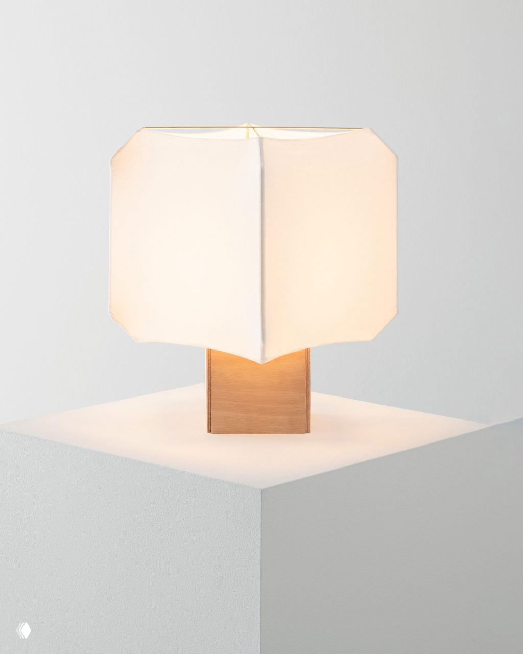 Настольная лампа с геометрическим текстильным абажуром на блочном деревянном основании, мягкий рассеянный свет в студийной съёмке.