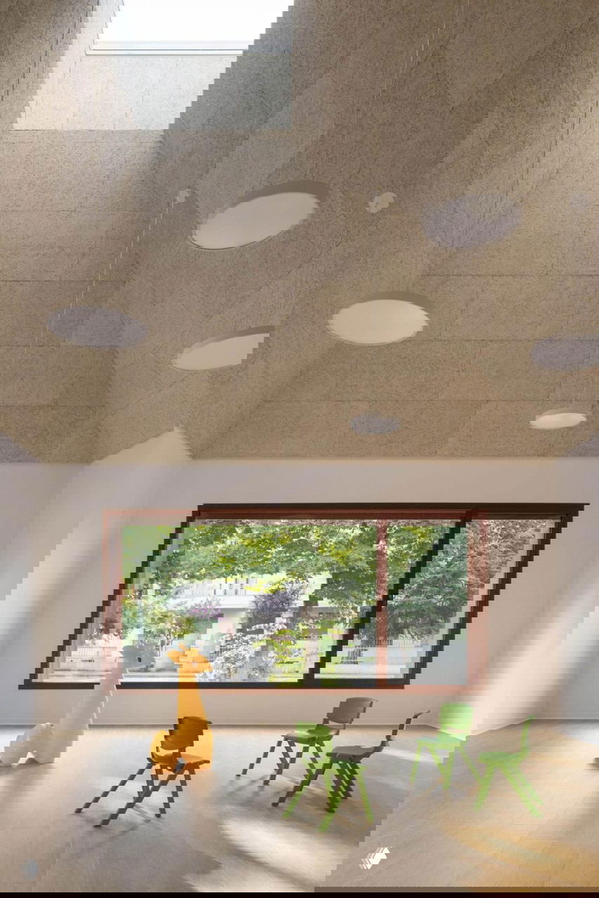 Игровой внутренний двор детсада с покрытием в терракотовых тонах, ребёнок играет с мячом на фоне облицованных стен и оконных проёмов