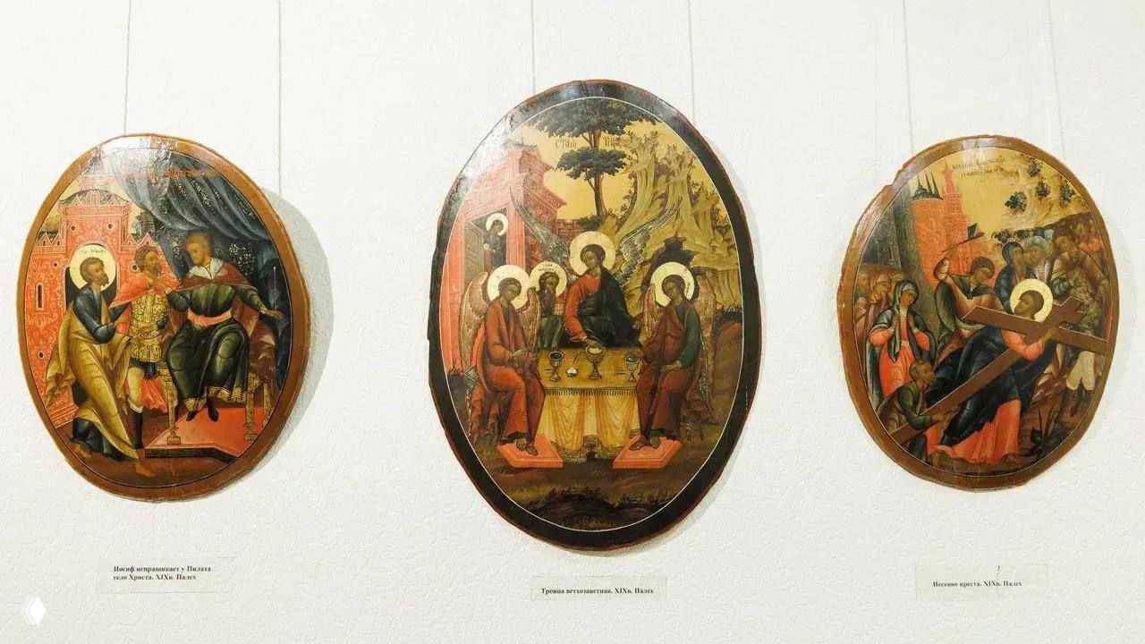 Три овальные старинные иконы на светлом фоне; видны фигурные сцены, орнамент и золотая позолота в музейной экспозиции.