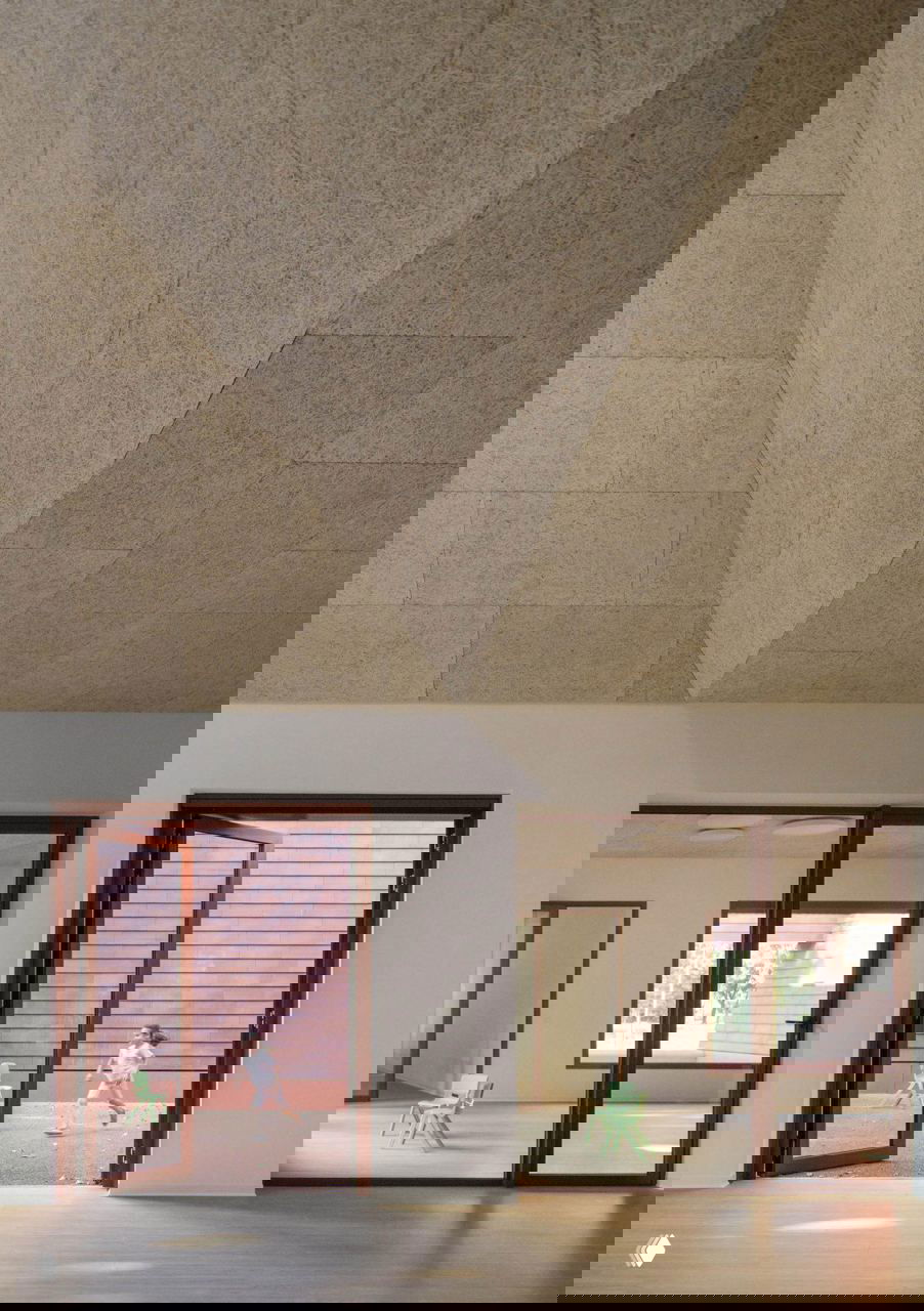 Интерьер с высоким потолком и акустическими панелями из древесного волокна, деревянный пол и большие окна создают светлое пространство для занятий