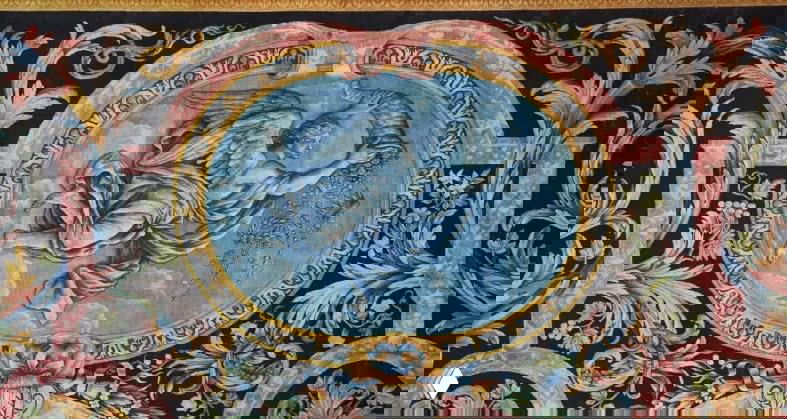 Деталь ковра с изображением летящей фигуры на синем фоне, окружённой орнаментальными гирляндами и филигранной текстурой ручного плетения.