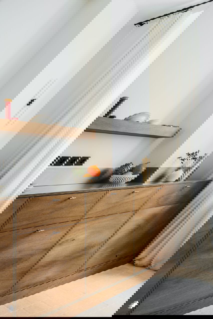 Мини-кухня с тёплыми деревянными фасадами и металлической столешницей, открытая полка и минималистичные аксессуары.