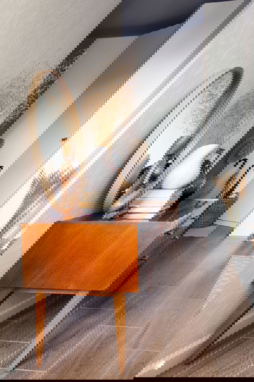 Прихожая с деревянным комодом, круглым зеркалом и сухими декоративными травами — тёплый ретро-штрих в оформлении маленькой квартиры.