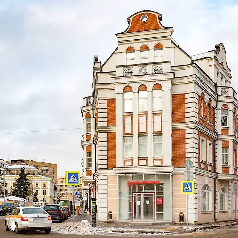 Крупное архитектурное здание в историческом районе Москвы — фасад с деталями в стиле позднего XIX–XX века, улица и пешеходный переход.