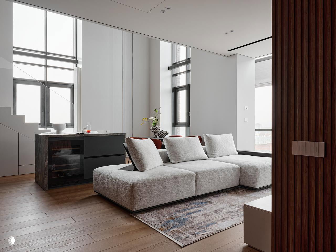 Гостиная у панорамных высоких окон: модульный низкий диван, мягкие текстуры, широкие окна и ровный деревянный пол в спокойной цветовой гамме.