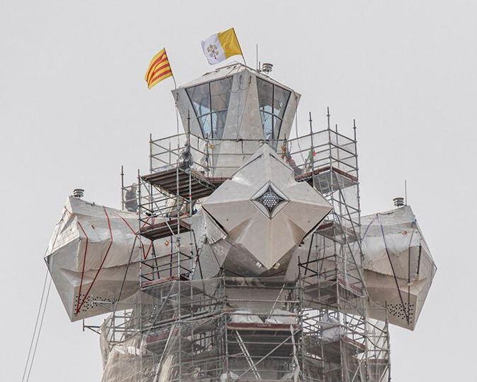 Временная платформа и защитная обшивка на одном из элементов башни с видимыми флагами и элементами отделки на фоне неба.