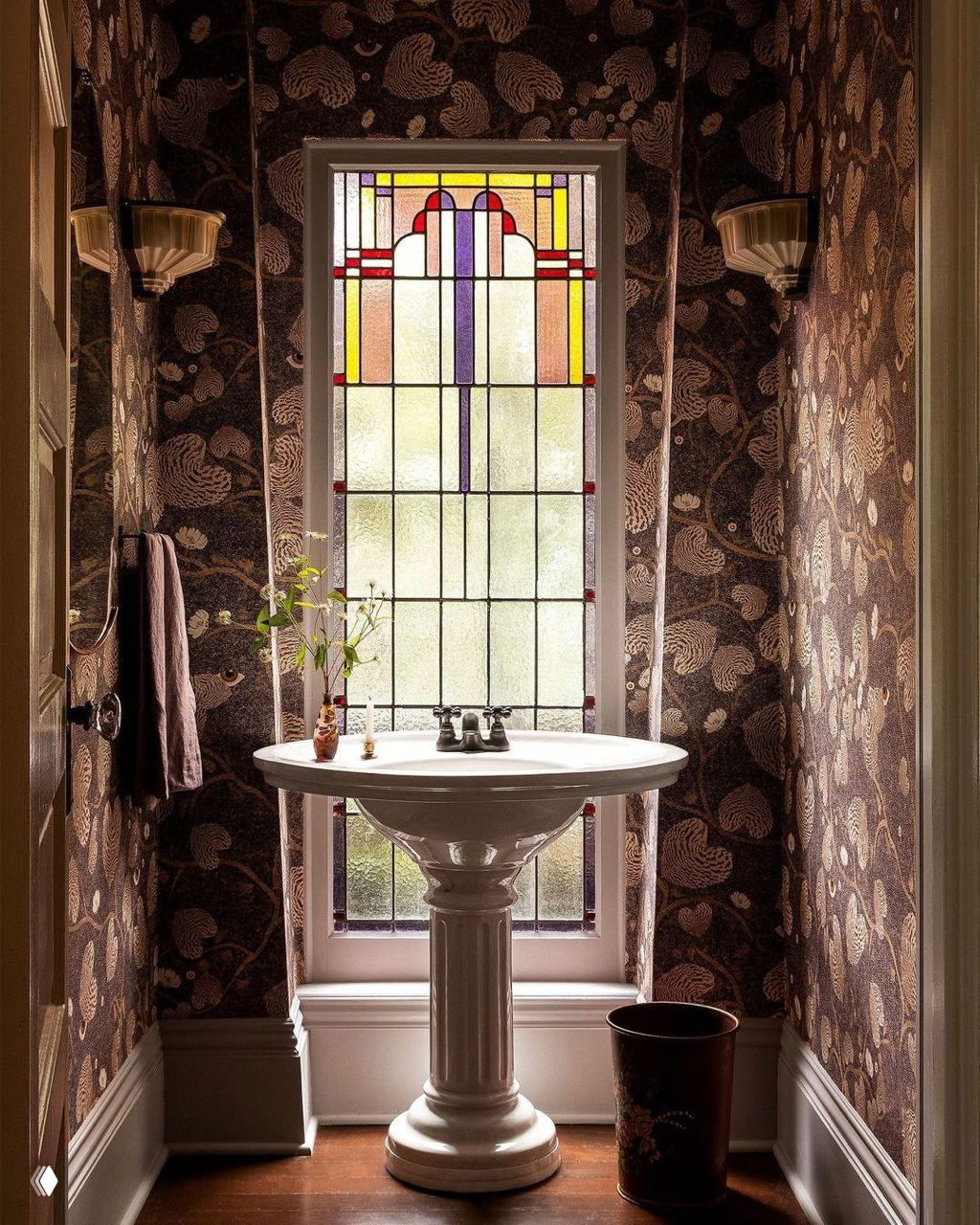 Уединённая небольшая туалетная комната с витражным окном и богато орнаментированными обоями в коричневых тонах — стильный ретро-акцент в пространстве.