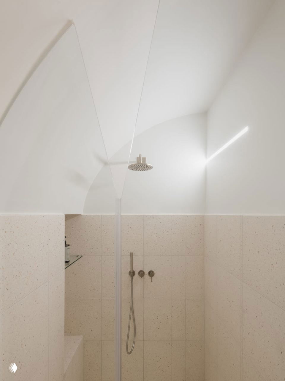 Ванная/душевая зона с белыми арками и бежевой плиткой по стенам; минималистичный душ с круглой лейкой и чистыми геометрическими линиями пространства.