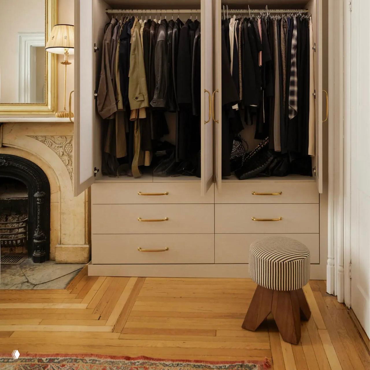 Открытый шкаф с вешалками и выдвижными ящиками в классическом интерьере; аккуратно висящая верхняя одежда и изделия на полках.