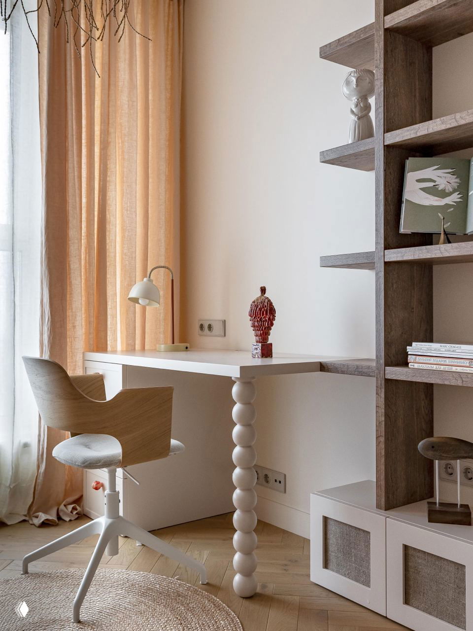 Рабочая зона с белым столом и необычной ножкой-шариками, деревянный стеллаж и тёплые льняные шторы в пастельной палитре; фото Виталины Ворошкевич.