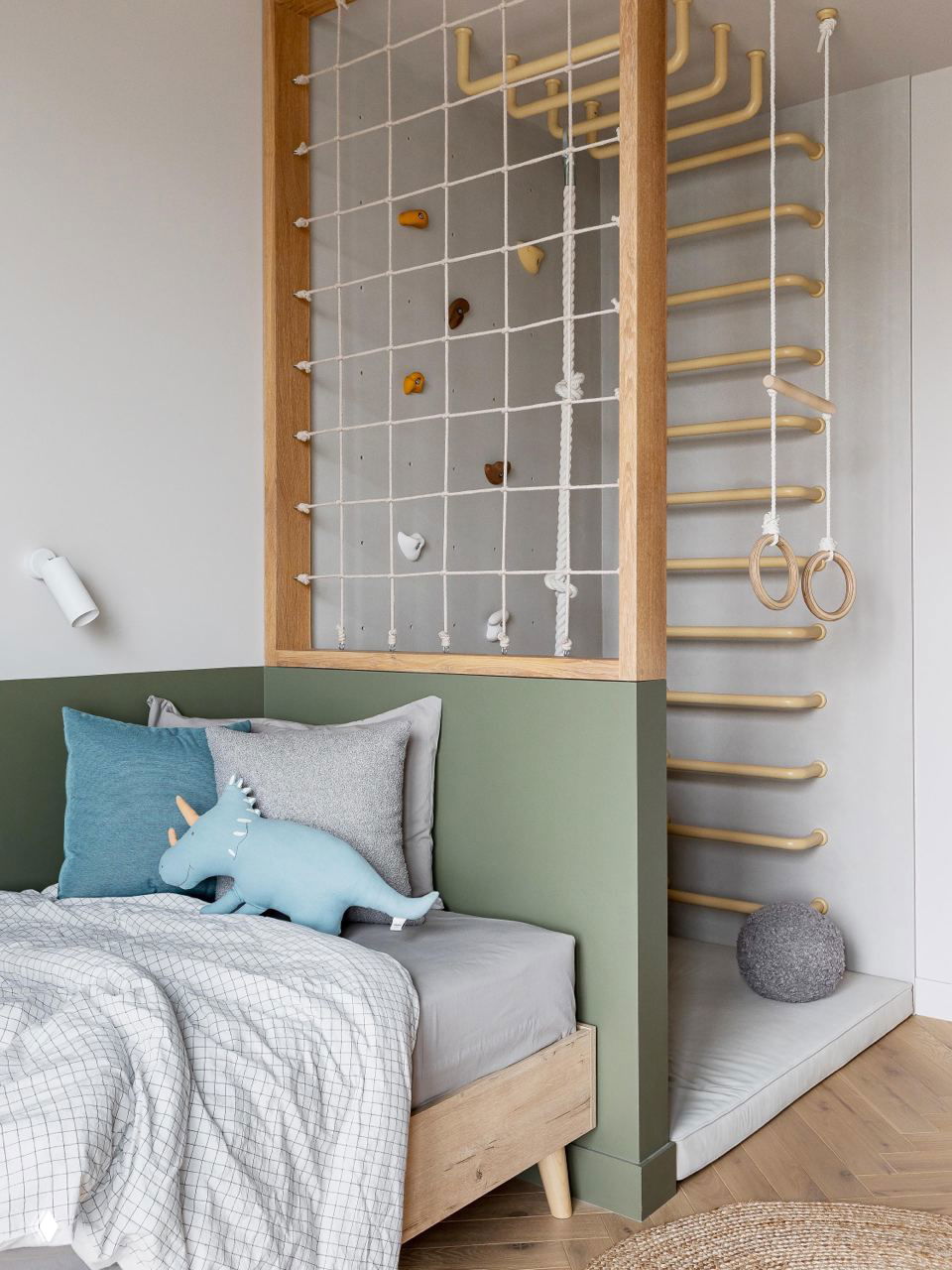 Детская игровая зона: деревянная восходящая стенка-лесенка, канатная сетка для лазанья, кровать с зелёной панелью и мягкие текстильные элементы; фото Виталины Ворошкевич.