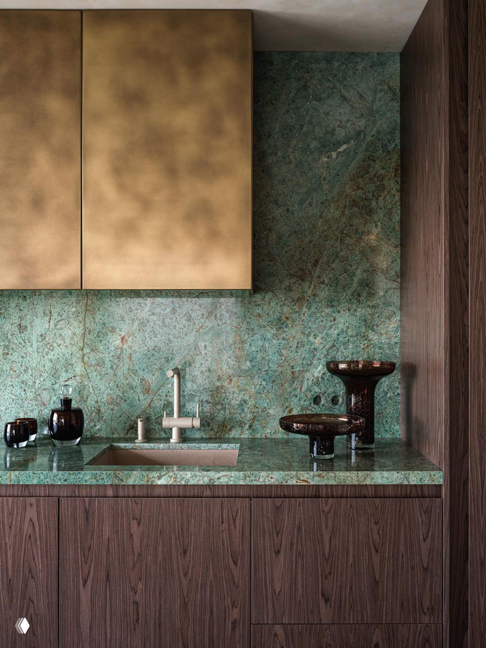 Кухонная рабочая зона с зелёным мраморным фартуком и столешницей, бронзовые фасады верхних шкафов и тёмные декоративные акценты у мойки.