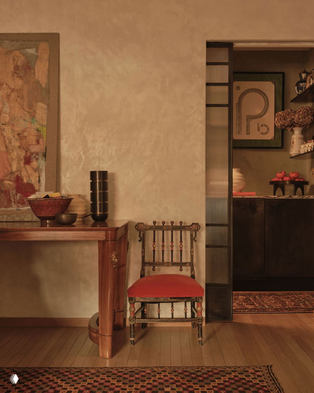 Интерьер с консольным столом и старинным стулом с красной обивкой на фоне нейтральных стен и декоративных аксессуаров.