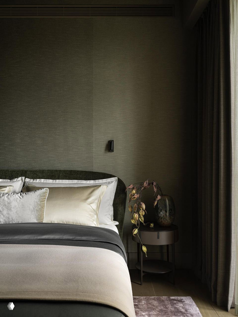 Спальня: аккуратно застеленная кровать с тёмно‑зелёной бархатной обивкой изголовья, мягкие текстуры постельных тканей и приглушённое боковое освещение.