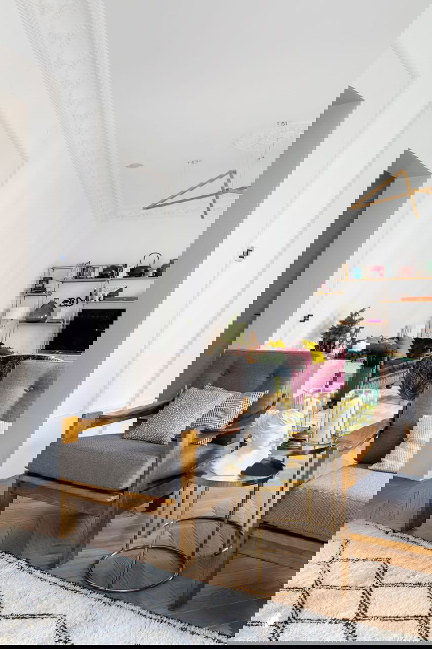 Гостиная: деревянные кресла с серой обивкой, бархатный диван и стильные журнальные столики на фоне белых стен с молдингами и высокой потолочной лепниной.