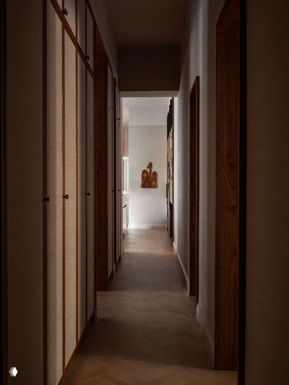 Длинный коридор с встроенными шкафами из ореха, мягким направляющим светом и тёплым деревянным паркетом, ведущий к приватным зонам квартиры.