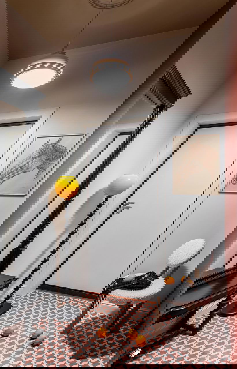 Прихожая с узорной плиткой на полу, высоким консольным зеркалом и яркой напольной лампой с жёлтым плафоном — ретро-нотки в небольшом входном пространстве.