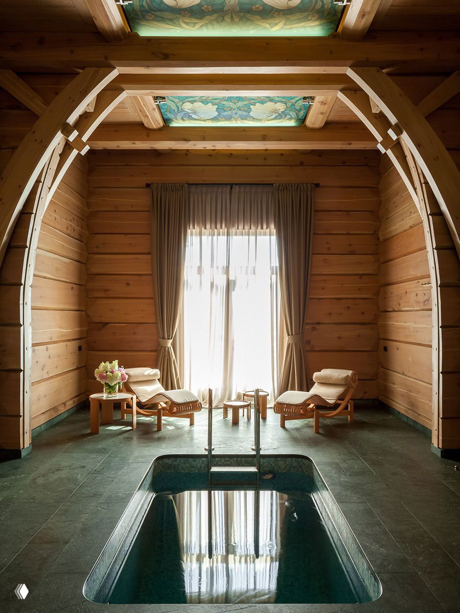 Внутренний SPA-зал с деревянными арками, приглушённым светом, купелью и шезлонгами — сочетание архитектурной графики и спокойной атмосферы.