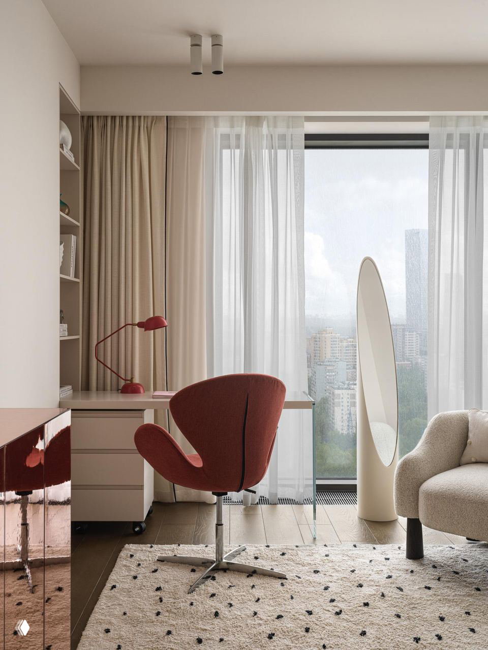 Рабочая зона у окна: стеклянный стол, винно‑красное кресло и высокий стоячий овал‑зеркало на фоне панорамного вида Москвы и лёгких полупрозрачных штор.