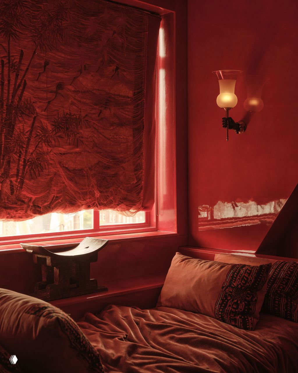 Интимный красный уголок квартиры: глянцевые красные откосы у окна, плотная драпированная штора и низкий диван с декоративными подушками.