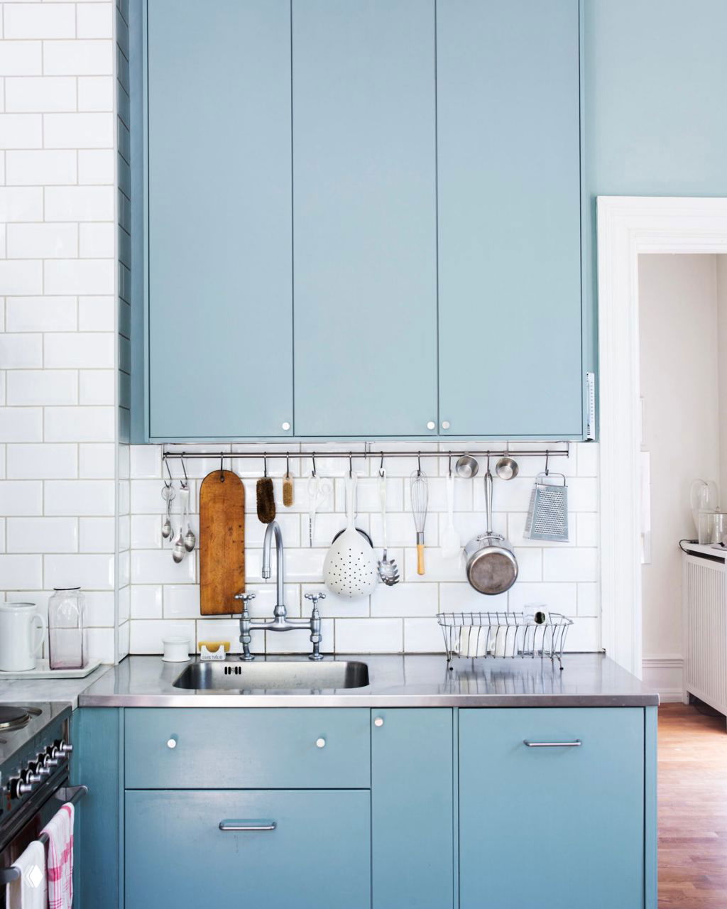 Минималистичная кухня с фасадами в холодном голубом оттенке, белой плиткой метро и металлической рабочей поверхностью — светлый функциональный интерьер.