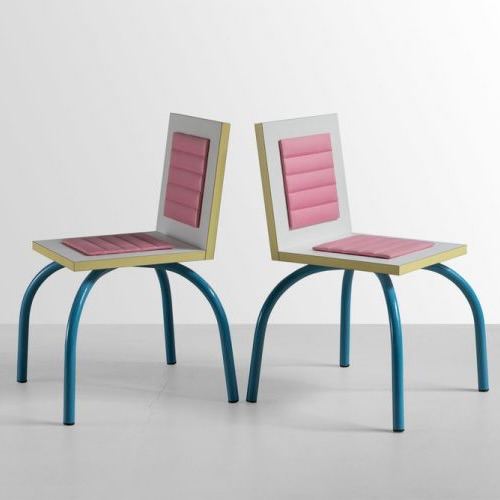 Пара стульев с квадратными сиденьями и изогнутыми синими ножками, пастельные вставки на спинках, современный экспериментальный дизайн на белом фоне.