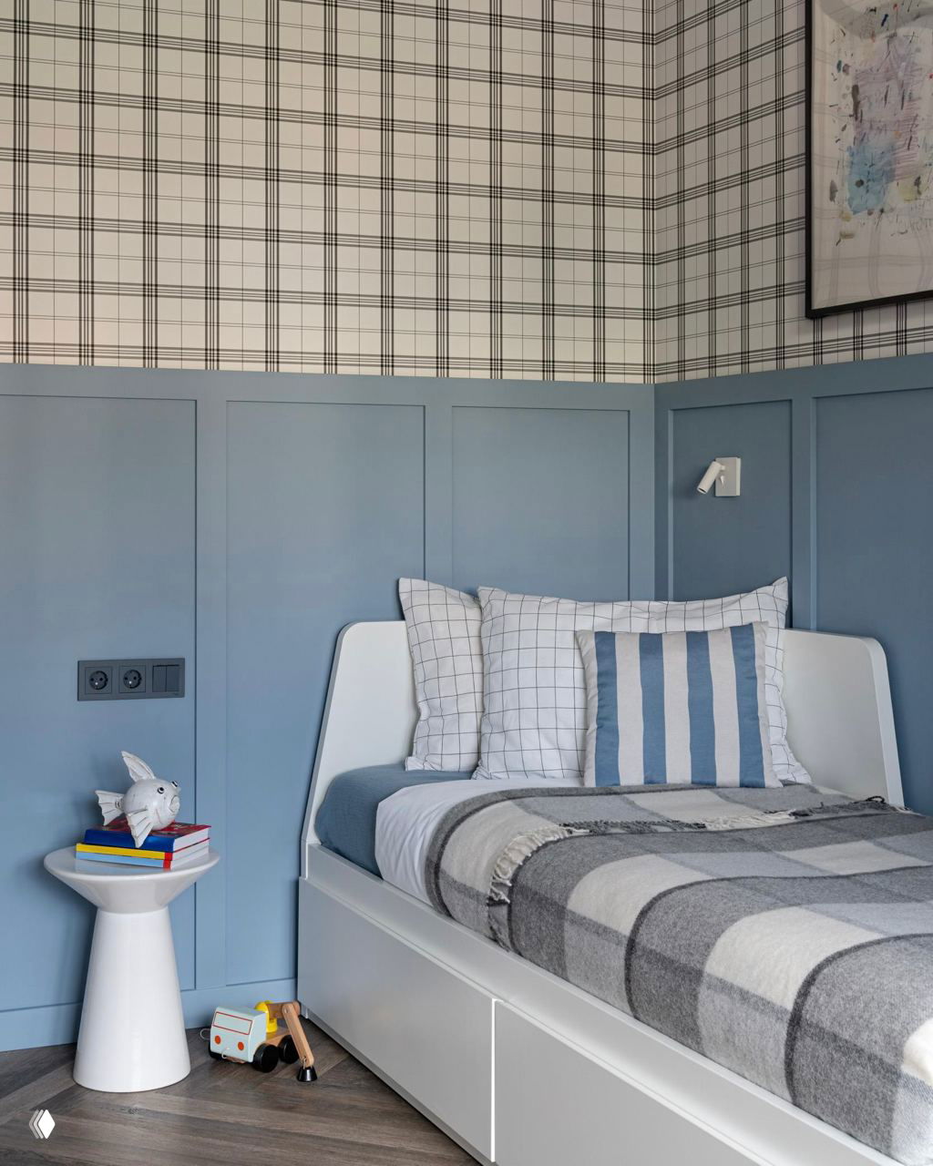Камера спальни/детской с облицовкой в бледно-голубых тонах, кровать с клетчатым текстилем и сдержанными декоративными элементами в спокойной палитре.