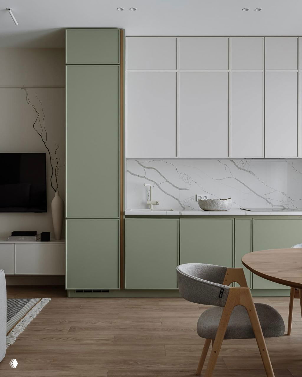 Кухня-гостиная в приглушённом нефритовом оттенке фасадов, белый мраморный фартук и деревянный пол — пример спокойной природной гаммы в интерьере.