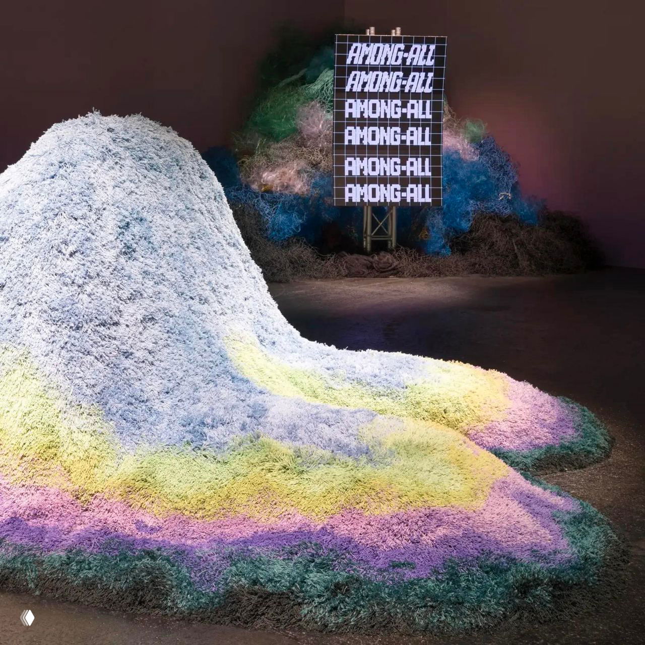 Крупный план насыпи из переработанных текстильных волокон с градиентной раскраской, лежащей на полу выставочного пространства Heimtextil.