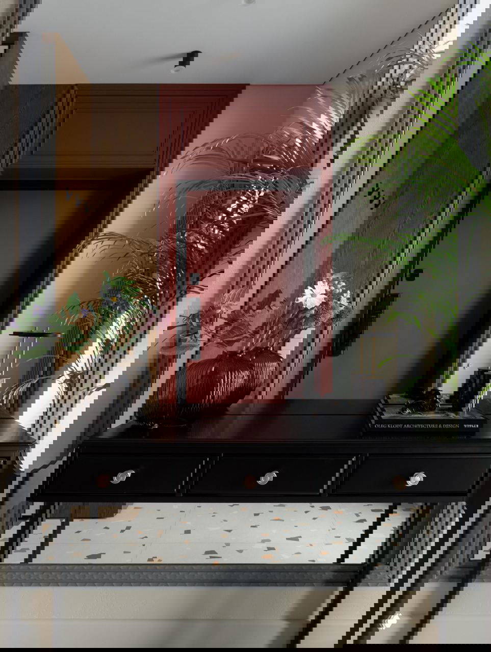 Прихожая проекта: винно-красная входная дверь, чёрный консольный стол, ваза с цветами, зеркало и напольная плитка с терраццо в квартире 42,5 м².