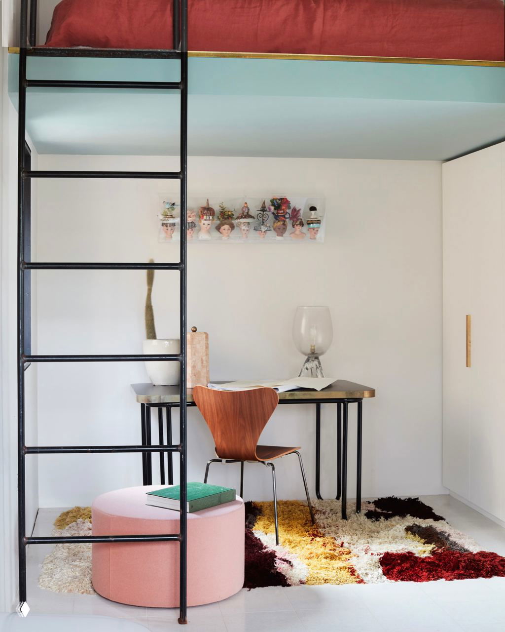 Небольшой домашний офис с лестницей и антресолью: компактный стол, стул и яркий коврик, уютная детская или студенческая версия рабочего угла.
