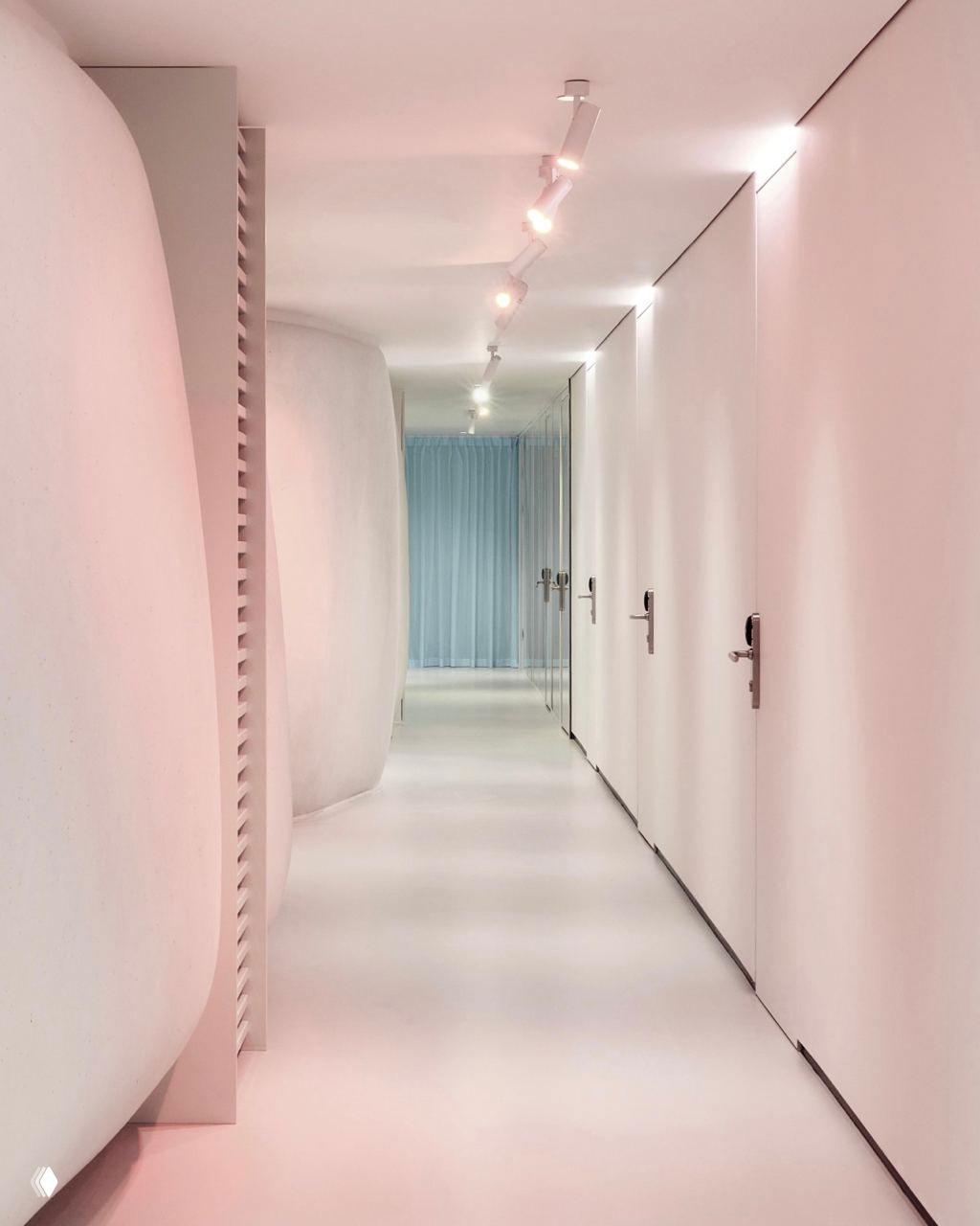 Длинный коридор в биохакинг-центре One с округлыми белыми объемами, встроенным трековым освещением и спокойной пастельной подсветкой.