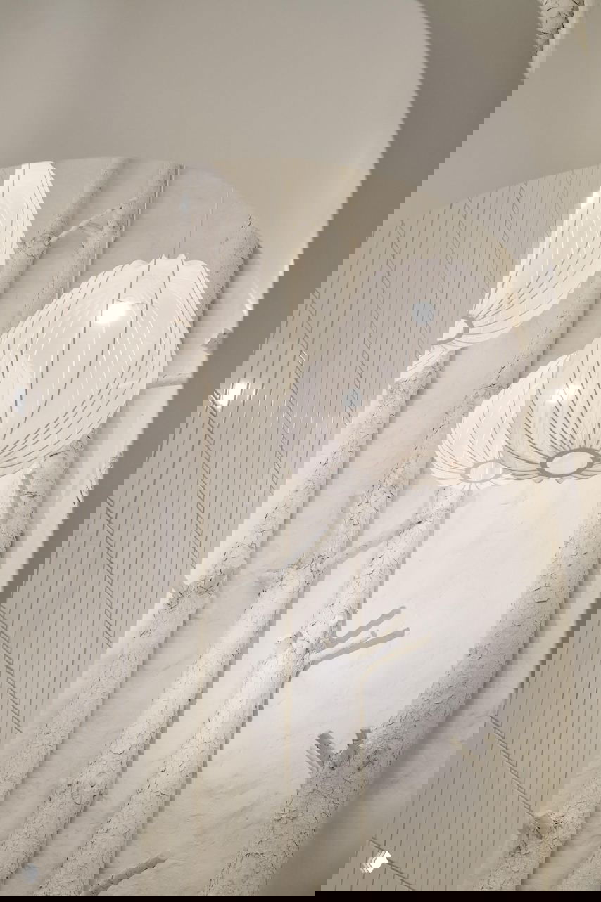 Белые подвесные светильники на фоне фактурной стены с имитацией берёзовых стволов; мягкое рассеянное освещение и натуральные текстуры в интерьере.