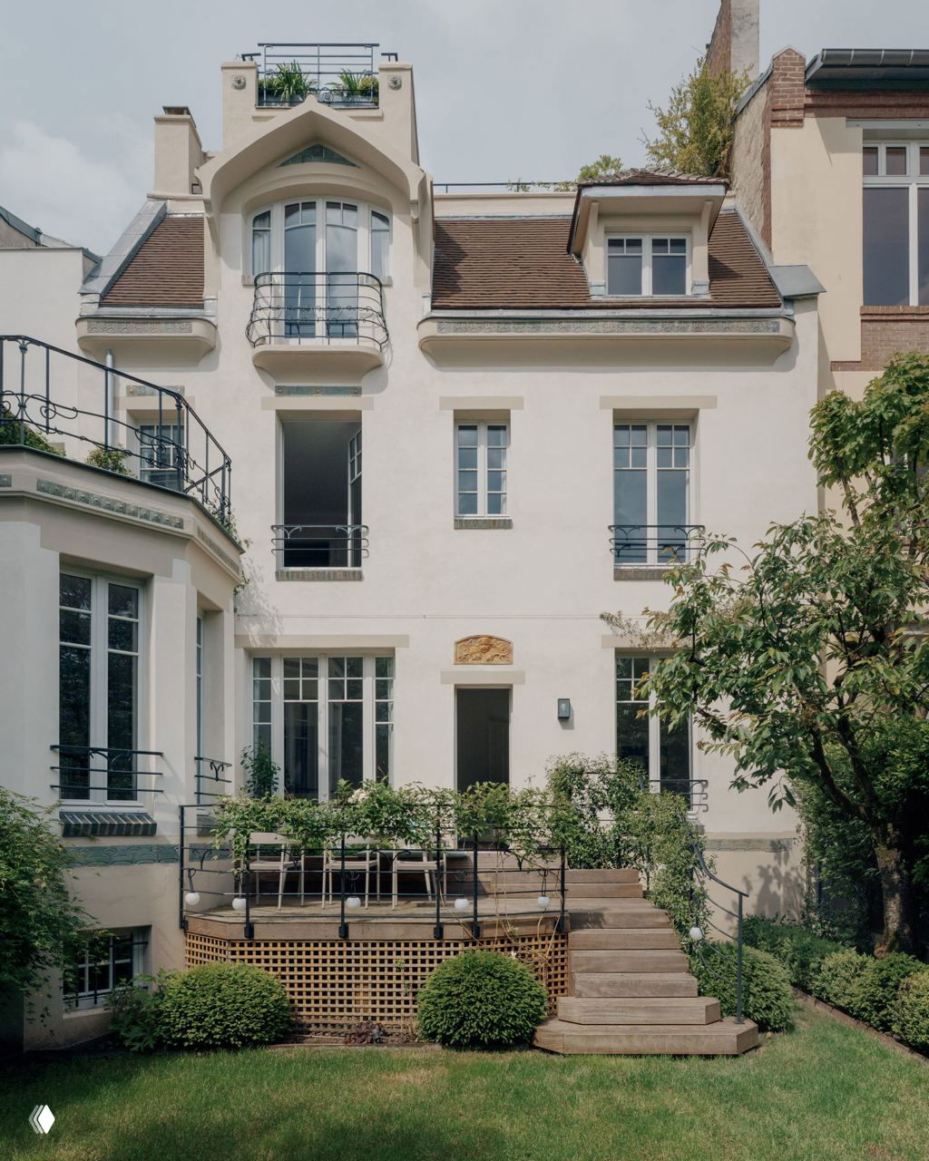 Задний фасад виллы с терассой и садом: ступени к террасе, балконы и характерные формы крыши в стиле начала XX века.