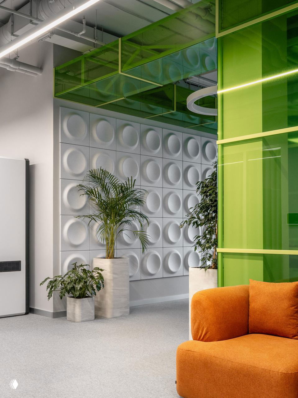 Интерьер с отражающими стеклянными конструкциями и зелёными стеклянными модулями в потолке, декоративные панели и зона с растениями.