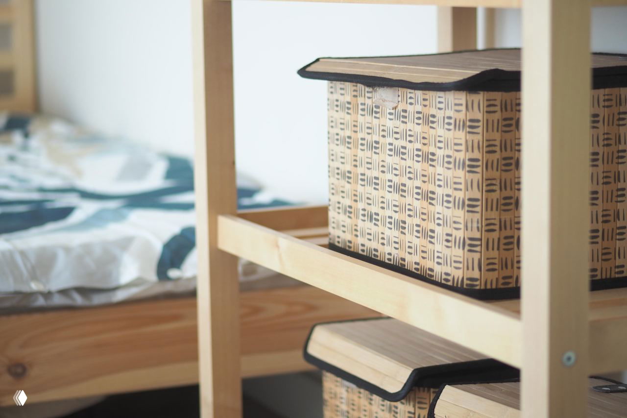 Плетеные коробки на полке рядом с кроватью — компактное хранение сезонных вещей и текстиля после сортировки и отбраковки.