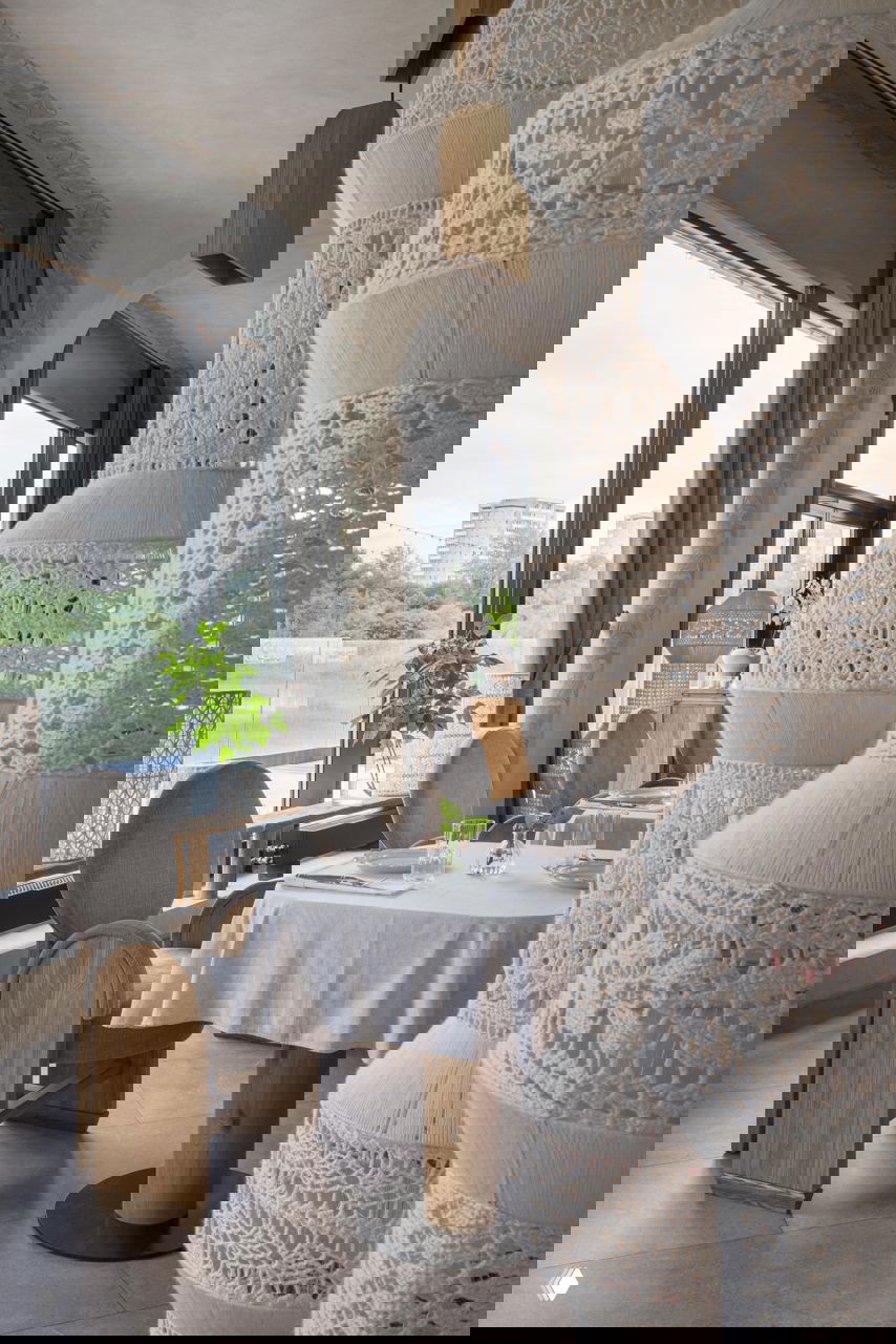 Зона столовой у панорамного окна: округлые спинки стульев на деревянных основаниях, белые скатерти и ажурные декоративные светильники из нитей.