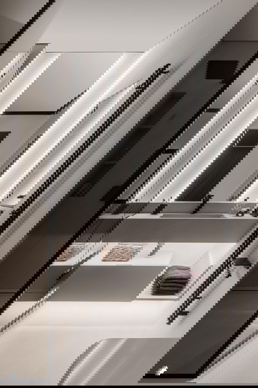 Современная мастер‑ванна: большое зеркало с подсветкой, подвесная консольная раковина, стеклянная душевая перегородка и минималистичная сантехника в тёмном цвете.