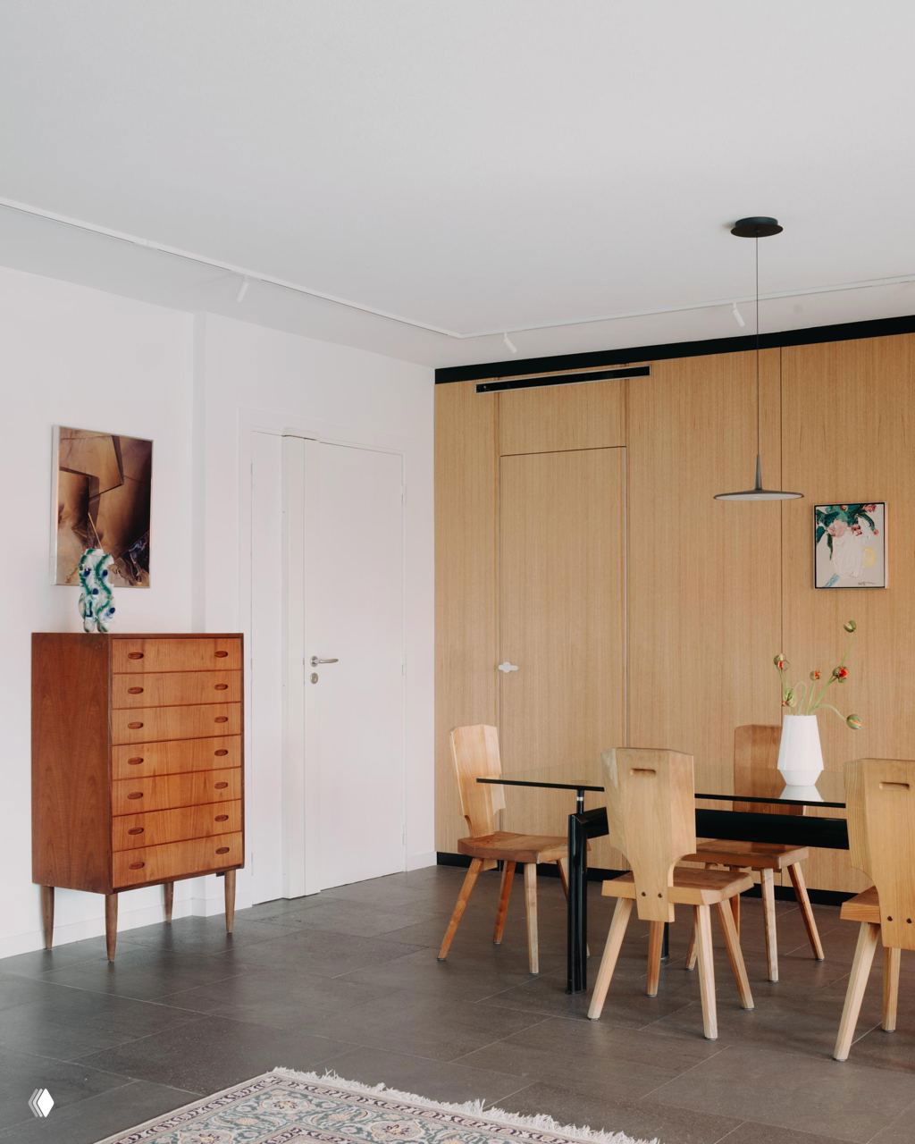 Столовая зона с деревянной стеновой панелью, простыми деревянными стульями и столом; светлый, спокойный дизайн с акцентами на натуральных материалах.