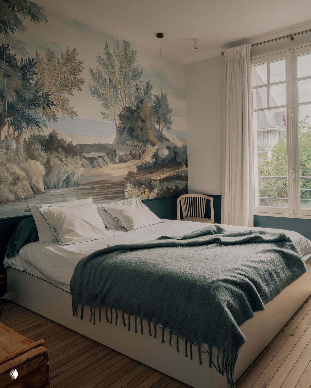 Спальня с настенной росписью-пейзажем, большим окном и спокойной текстильной палитрой — элемент исторического декора интегрирован в интерьер.