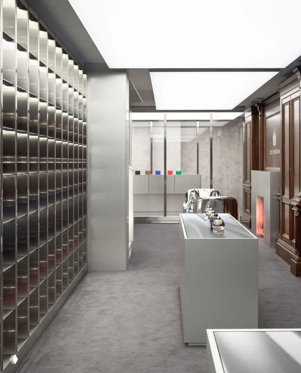 Центральный проход бутика: минималистичная центральная витрина с ароматами на фоне гладких стен и обрамления из полированного металла и дерева