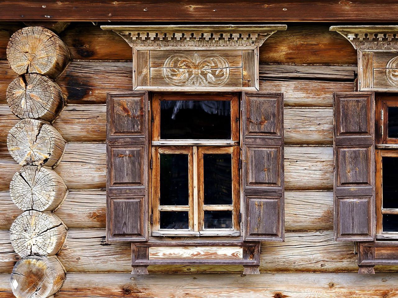 Деревянный фасад с резными наличниками и ставнями, крупный план традиционного архитектурного декора суздальских домов и мастерства плотников.