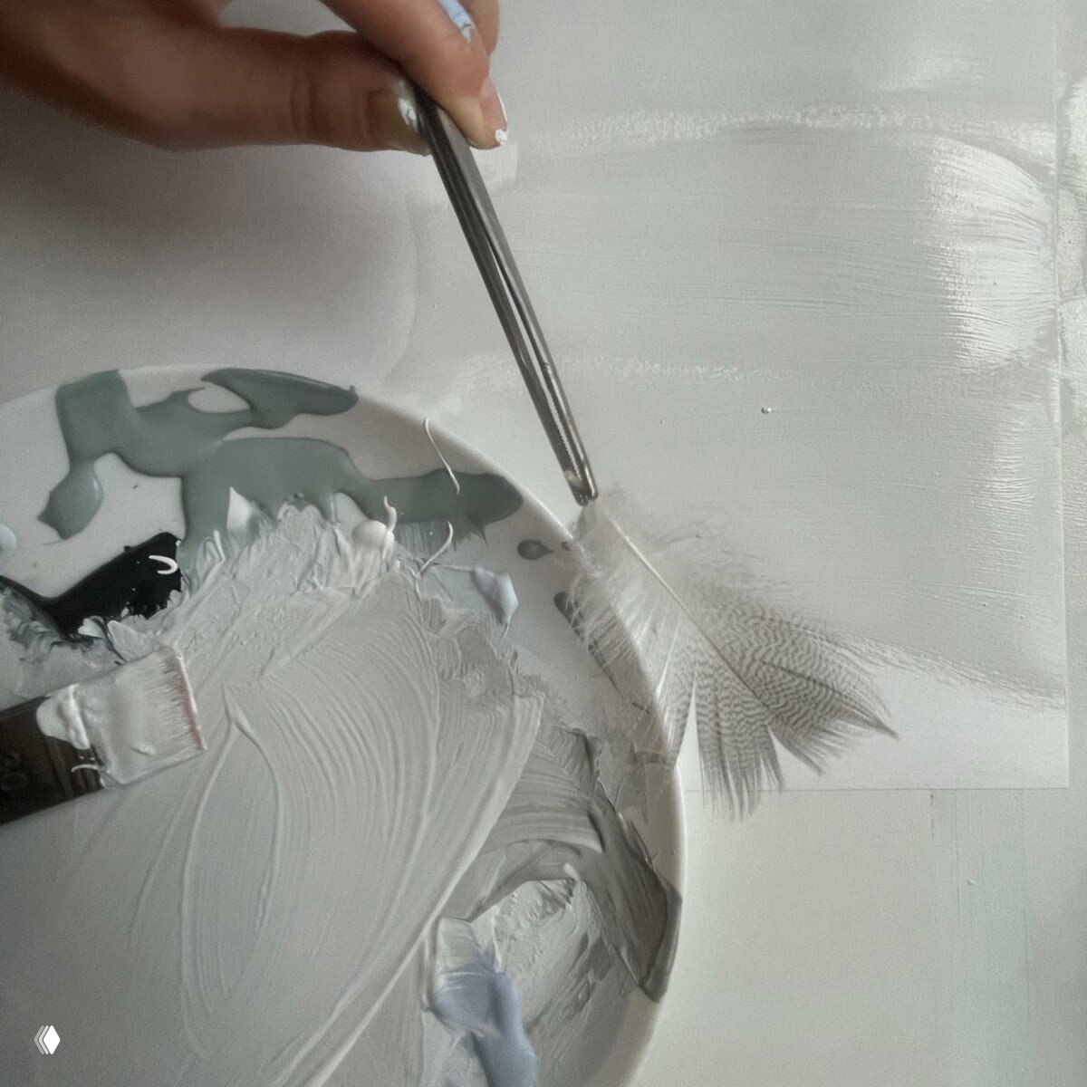 Палитра красок на тарелке, шпатель и пинцет держат перо над пробной поверхностью, демонстрируется смешение и тест полутоновых оттенков.