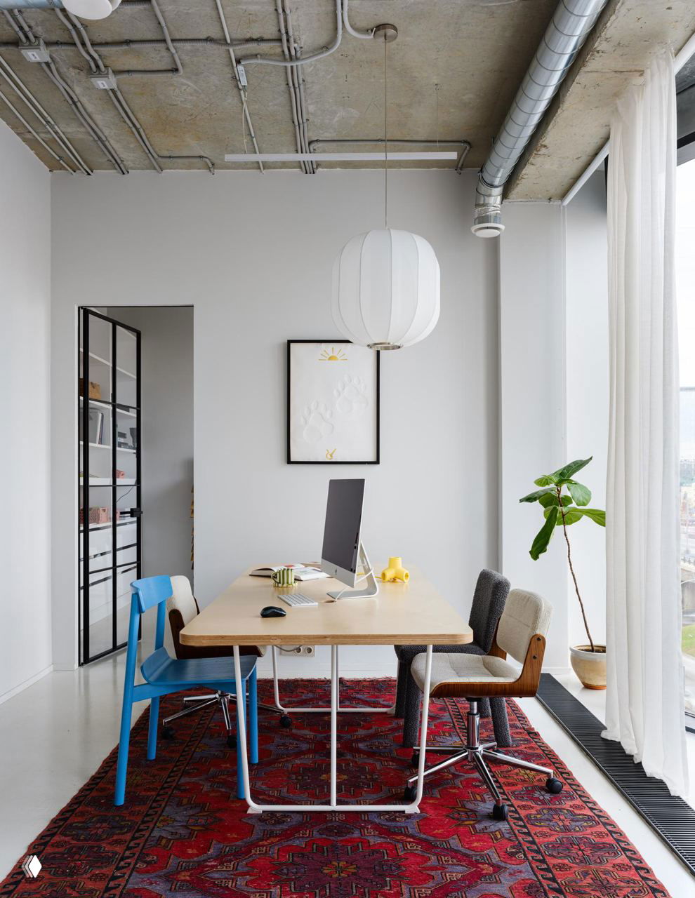 Стол для переговоров у большого окна: светлый стол, синие и серые стулья, восточный ковёр и высокие шторы создают уютный уголок для встреч.