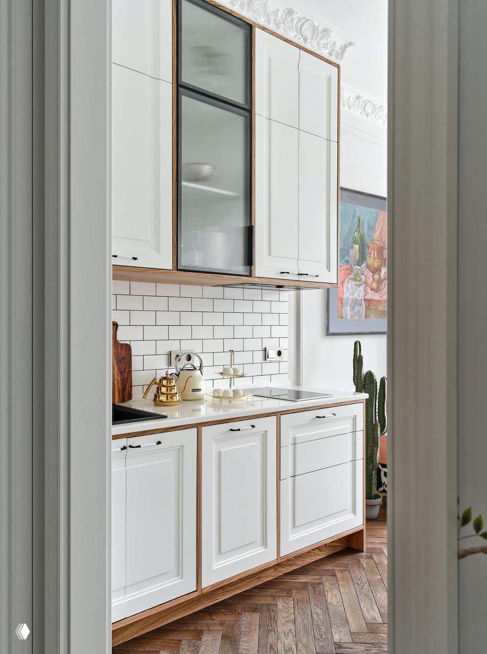 Узкая кухня в белых классических фасадах с деревянной отделкой, метрообразная плитка на фартуке и аксессуары в ретростиле на столешнице.